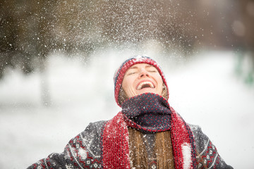 Happy beautiful woman having fun with snow outdoors in winter scenery