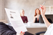 © stock28studio - Closeup of resume in hands of HR with two women on background. Selective focus