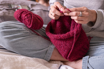 Hands knitting sweeter with needles close up