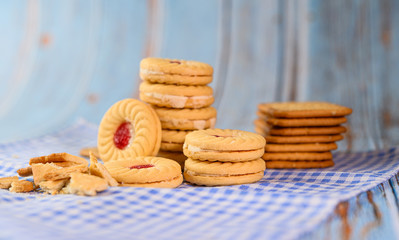 sandwich cookies with strawberry cream placed on a blue and white cloth