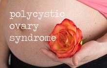 Words POLYCYSTIC OVARY SYNDROME. Young Pregnant Woman Keeps Natural Rose Blossom Close To Her Belly.