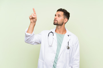 Wall Mural - Young doctor man over isolated green wall touching on transparent screen