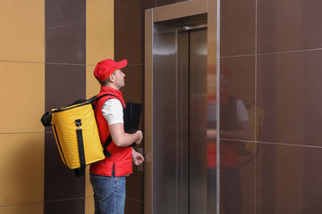 Poster - Male courier with thermo bag and clipboard waiting for elevator. Food delivery service