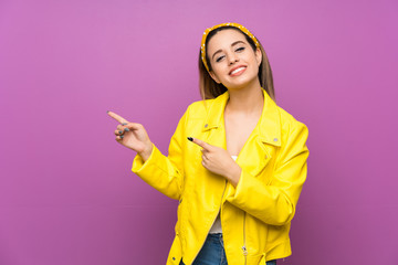 Wall Mural - Young woman over purple background pointing finger to the side