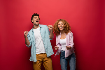 Wall Mural - beautiful excited couple in casual clothes isolated on red