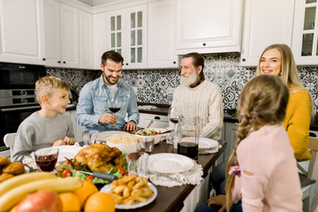 Wall Mural - Portrait of big family sitting at festive table and looking at each other, talking and smile. Thanksgiving dinner concept