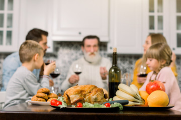 Wall Mural - Roasted Turkey. Thanksgiving table served with turkey, salad, cookies and fresh fruits, wine. Happy family at the table on the background