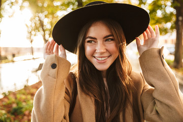 Sticker - Portrait of pleased woman wearing coat and hat walking in autumn park