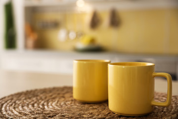 Sticker - Yellow cups on wicker mat in kitchen. Space for text