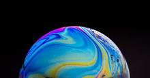 Close Up Of A Colorful Soap Bubble Isolated On A Black Background, Looking Like A Planet In Space.