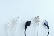 Electrical Plugs From Electrical Appliances In White And Black On A White Background. View From Above.