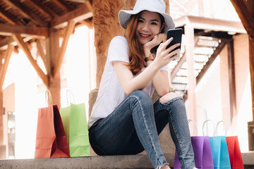 Young woman happy with shopping bags. Easy E-commerce Website Shop by Smartphone, Laptop. Business and modern lifestyle concept