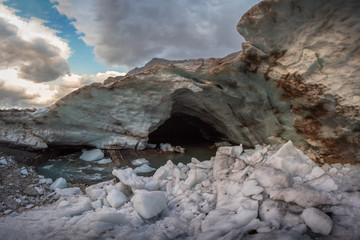 Canvas Print - Entrance to the snow cave of the Alibek mountain glacier in Dombay with high walls of frozen snow