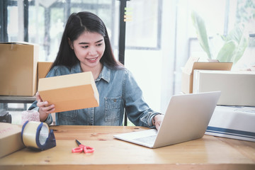 Beautiful young asian business owner working with computer and tablet standing in workshop.Responding on business e-mail,writing the order of product customer orders.