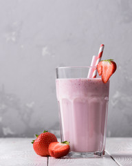 Wall Mural - Strawberry protein shake on a white wooden background. Fresh milkshake with strawberries on a light table. A glass of strawberry smoothie.