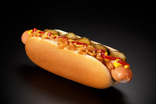 Danish Hot Dog With Pickled Cucumbers, Fried Onions, Ketchup And Mustard On A Black Background.