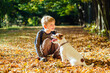 © Iryna - Eight year old blond boy caressing his dog Jack Russell Terrier playing with ball and sitting down on the stairs outdoor in evening sunset beautiful light autumn season. True love friendship concept.