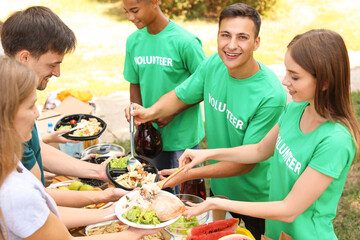 Wall Mural - Young volunteers giving food to poor people outdoors