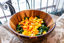 Closeup Of One Large Wooden Salad Bowl With Chopped Green Kale And Orange Yellow Bell Peppers As Vegan Lunch Or Dinner On Balcony Chair