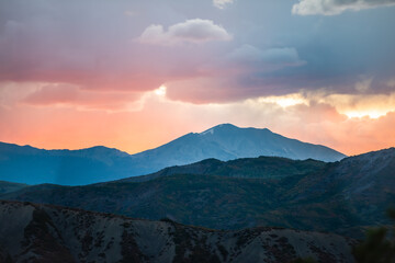 Wall Mural - Orange red cloudy sunset sun rays in Aspen, Colorado with rocky mountains peak and vibrant color of clouds at twilight with mountain ridge silhouette