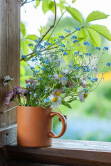 spring flowers in a clay mug on the background of green garden, spring mood