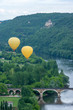 Two yellow hot air ballons flying over the Dordogne river with chateau castlenaud in the background Dordogne France