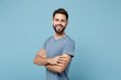 © ViDi Studio - Young smiling cheerful handsome man in casual clothes posing isolated on blue wall background, studio portrait. People sincere emotions lifestyle concept. Mock up copy space. Holding hands crossed.