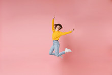 Funny Young Brunette Woman Girl In Yellow Sweater Posing Isolated On Pastel Pink Background In Studio. People Lifestyle Concept. Mock Up Copy Space. Having Fun, Fooling Around, Rising Hands, Jumping.