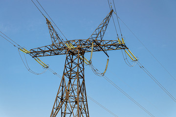 Power Transmission Tower. Air hi-voltage electric line supports on a blue sky background. Electricity garlands and insulators with electric wires on a top steel mast support.