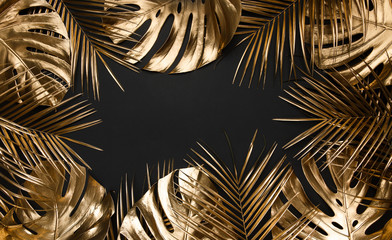 Wall Mural - Gold painted tropical leaves on black plain paper background.