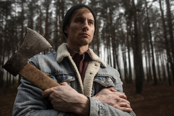 Strong lumberjack with the ax in the forest.Stylish lumberman getting ready for work. Lifestyle.