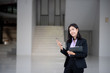 © Tanaban - An Asian manager smiled to send a formal message to a friend on a smartphone.