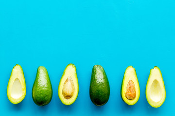 Avocado pattern - halfs of fruit - on blue background top view copy space