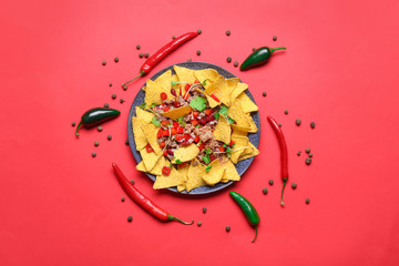 Plate with tasty chili con carne and nachos on color background