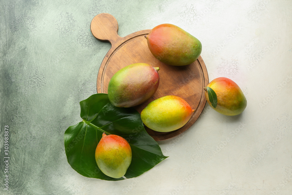Board with mango fruit on light background