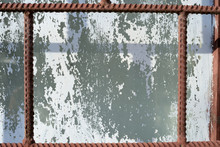 Old Window Painted By White Paint Behind A Rusty Brown Bars On A Sunny Day. Abstract Background