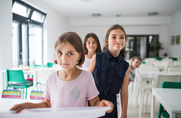 Wall Mural - Group of cheerful small school kids with plastic trays in canteen, walking.