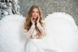 Beautiful young angel woman with big white wings near Christmas tree. Angel. Beautyful girl angel. Christmas.