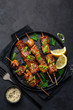 © anna_shepulova - Teriyaki salmon skewers on black plate