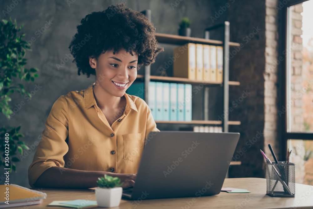 Photo of cheerful positive mixed-race girl smiling toothily working on presentation about her corporation using laptop on desktop - obrazy, fototapety, plakaty 