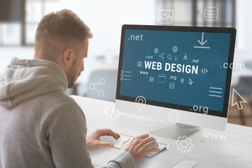 Fototapete - Web design studio concept. Guy work on computer with Web design text surrounded by web site parts and domain extensions.