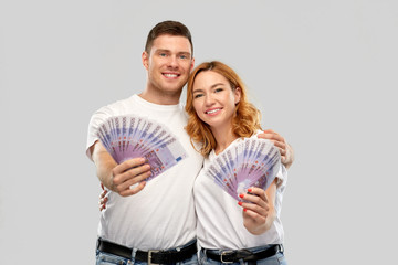 Poster - finance, saving and people concept - portrait of happy couple in white t-shirts with euro money over grey background