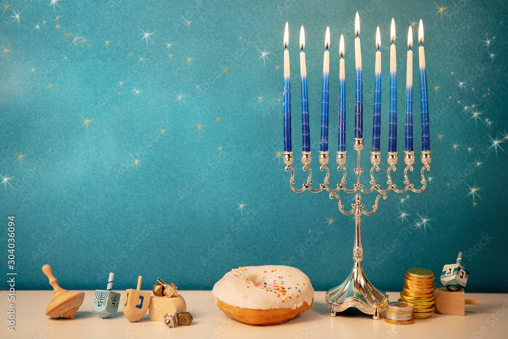 concept of of jewish religious holiday hanukkah with glittering raditional chandelier menorah, spinning top toys (dreidel), a doughnut and chocolate coins - obrazy, fototapety, plakaty 