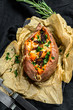 Baked sweet potato stuffed with cheese and bacon. Black background. Space for text