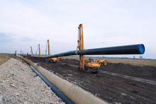 Pipeline Construction For Natural Gas. Heavy Duty Construction Machines Carrying And Placing Gas Pipe Into The Ground.