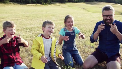 Poster - Group of school children with teacher on field trip in nature, playing.