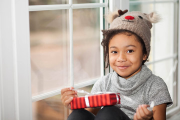 Happy adorable african american child girl opens a christmas present in a red box 