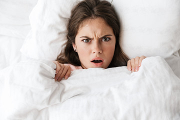 Top view of an angry young girl resting in bed at the bedroom