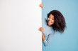 © deagreez - Photo of wavy cheerful positive nice pretty girlfriend looking at empty space in white blank banner hiding behind it smiling toothily isolated blue pastel color background