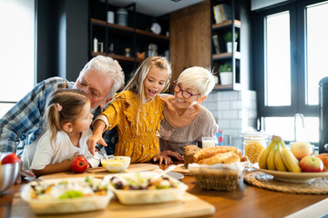 Wall Mural - Happy grandchildrens girls having breakfast with her grandparents